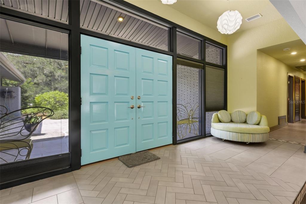 An entryway features light blue double doors, herringbone tile flooring, and a curved green sofa — 2634 COLLINS AVENUE, LAKELAND, FL