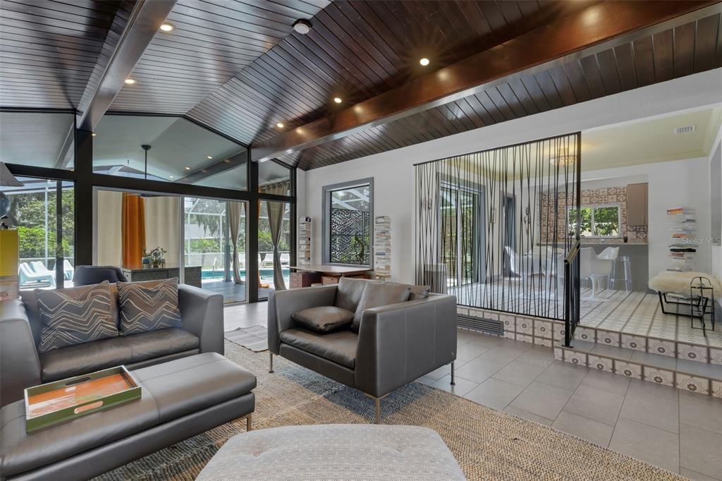 A living room with a vaulted wood ceiling, gray leather furniture, and a string room divider — 2634 COLLINS AVENUE, LAKELAND, FL