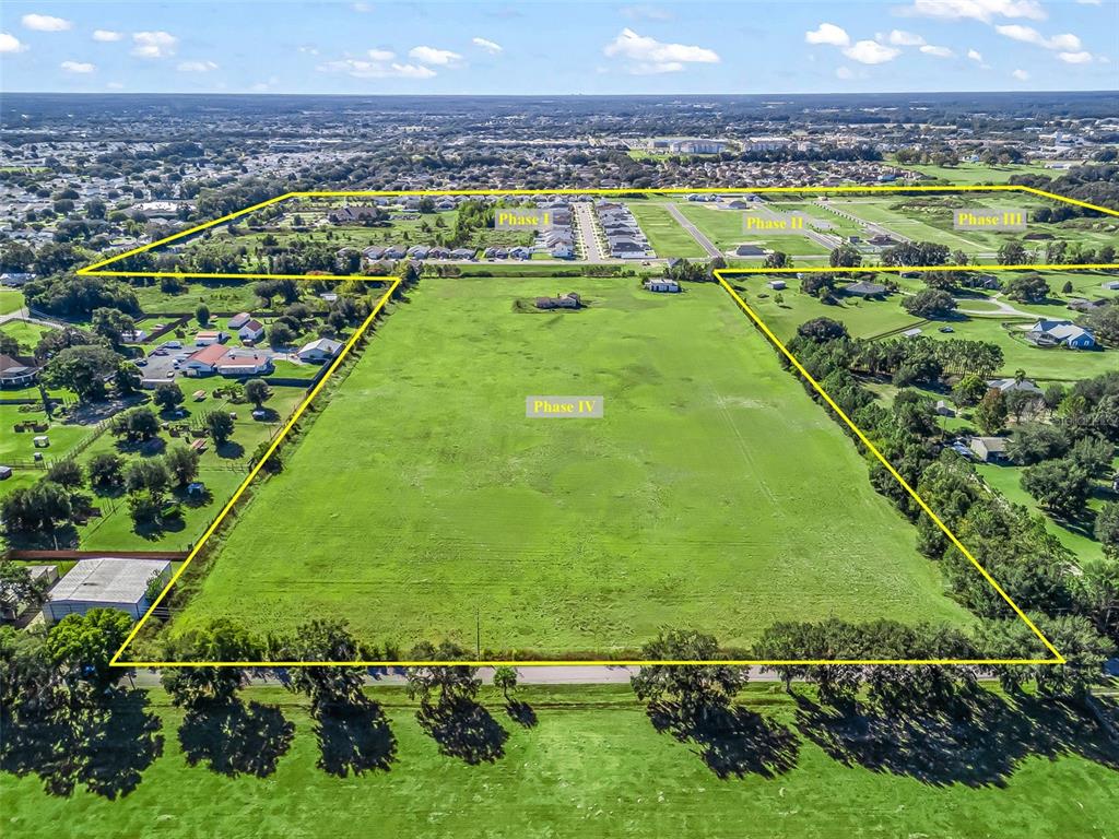 An aerial view shows a large, undeveloped grassy field labeled Phase IV adjacent to residential developments — NE 125TH LOOP, PHASE 2, OXFORD, FL
