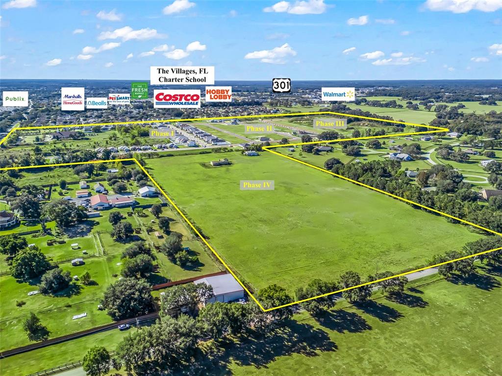 This aerial view shows a large, undeveloped grassy plot divided into four phases near retail stores — NE 125TH LOOP, PHASE 2, OXFORD, FL