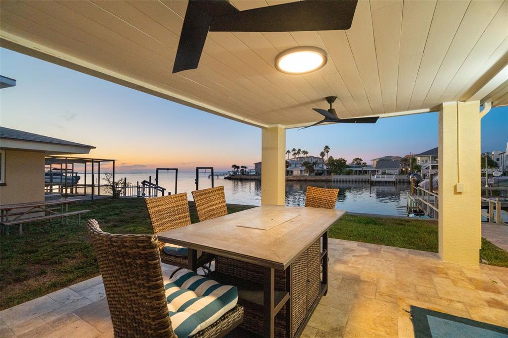 A covered patio with a dining set overlooks a waterfront canal at sunset — 2288 EDYTHE DRIVE, DUNEDIN, FL