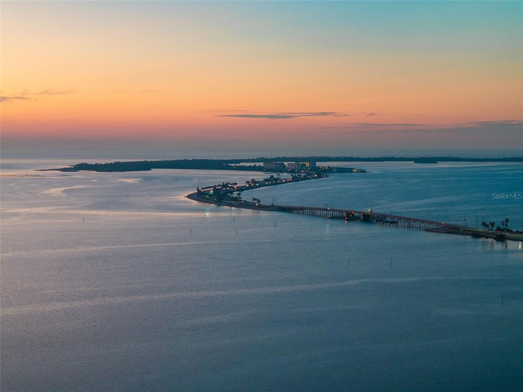 An aerial view shows a long bridge connecting land masses over water at sunset — 2288 EDYTHE DRIVE, DUNEDIN, FL
