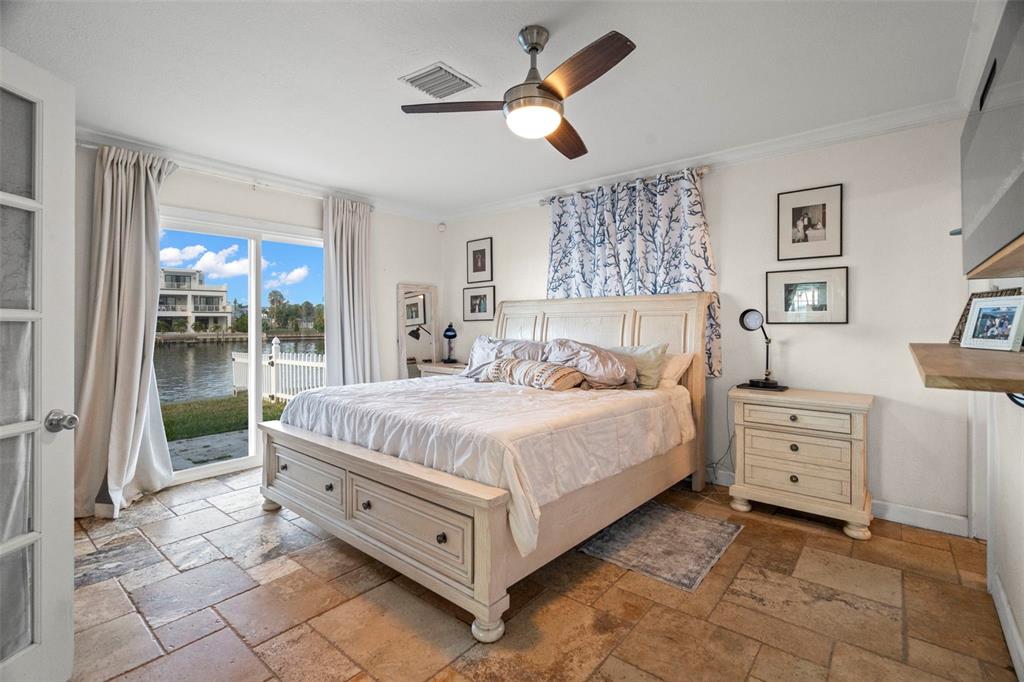 A bedroom with a bed, tile flooring, and a sliding door overlooking a canal — 2288 EDYTHE DRIVE, DUNEDIN, FL
