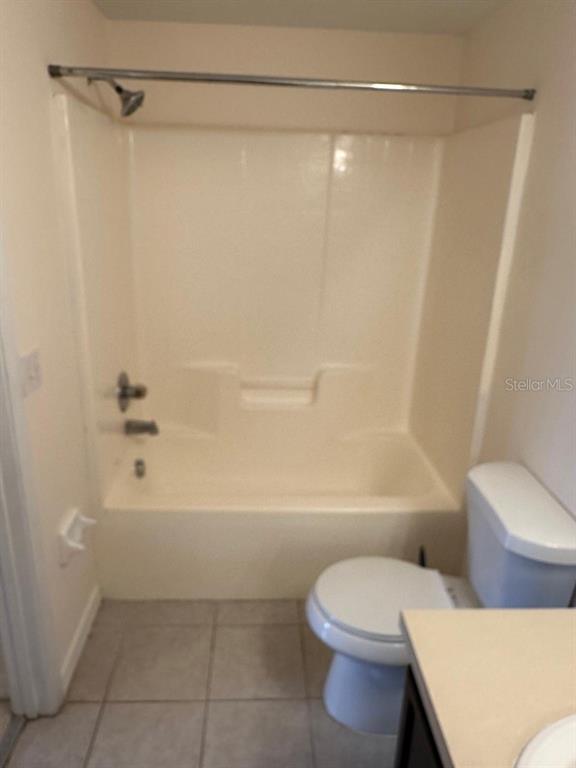 A bathroom featuring a beige fiberglass tub and shower surround next to a white toilet — 6425 CYPRESSDALE DRIVE UNIT 101, RIVERVIEW, FL