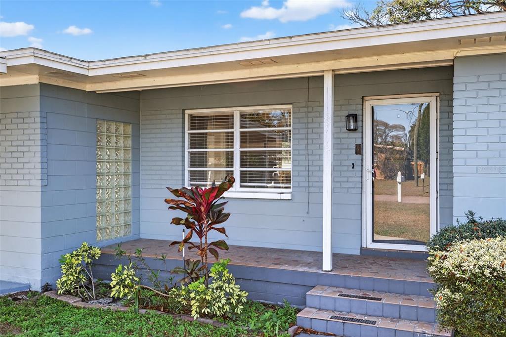The exterior of a light blue house features a glass block window and a front porch — 2714 W GRACE STREET, TAMPA, FL