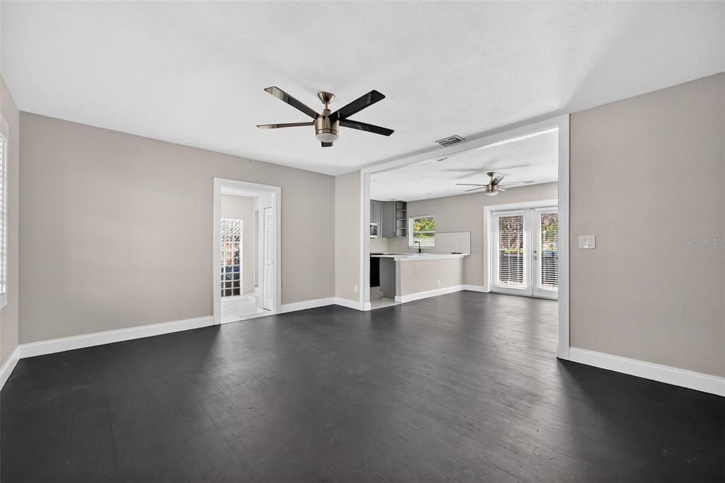 A living room with dark wood floors, a ceiling fan, and an open kitchen view — 2714 W GRACE STREET, TAMPA, FL