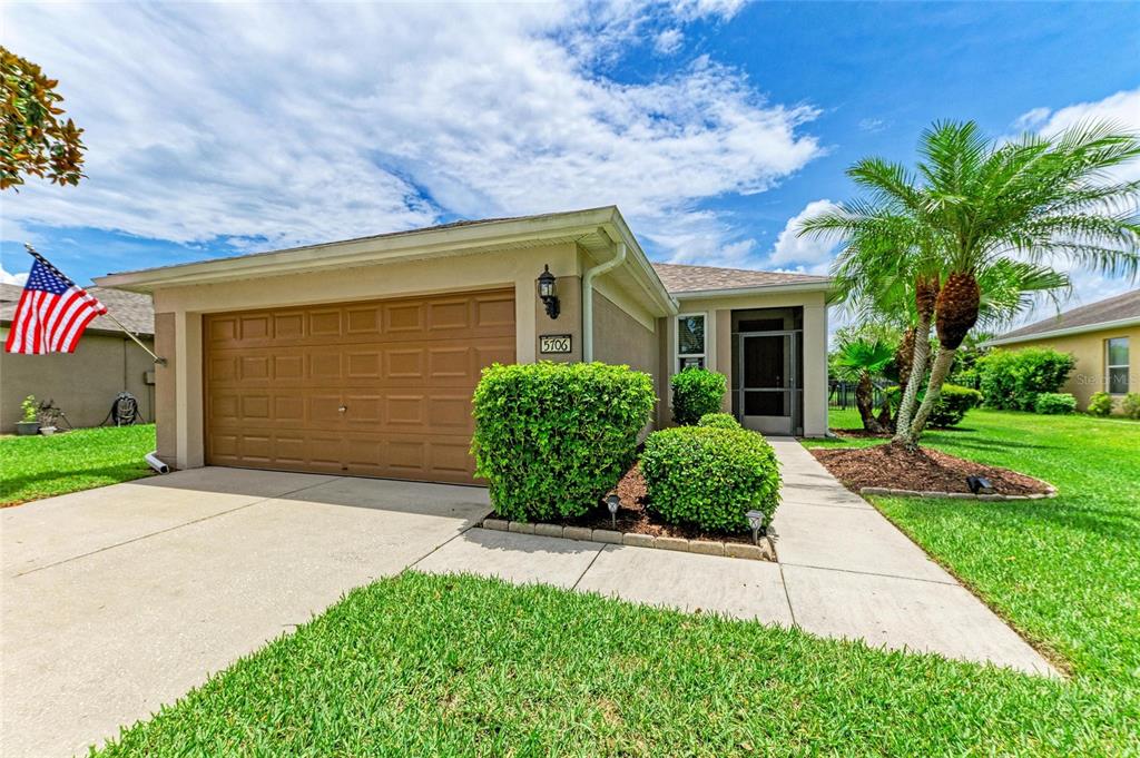 A single-story house with a tan stucco exterior, a two-car garage, and a palm tree — 5706 106TH AVENUE E, PARRISH, FL