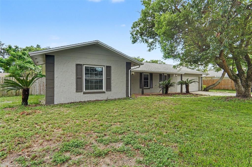 A single-story house with a gray stucco exterior, dark shutters, and a large front yard — 960 APPLE LANE, ALTAMONTE SPRINGS, FL