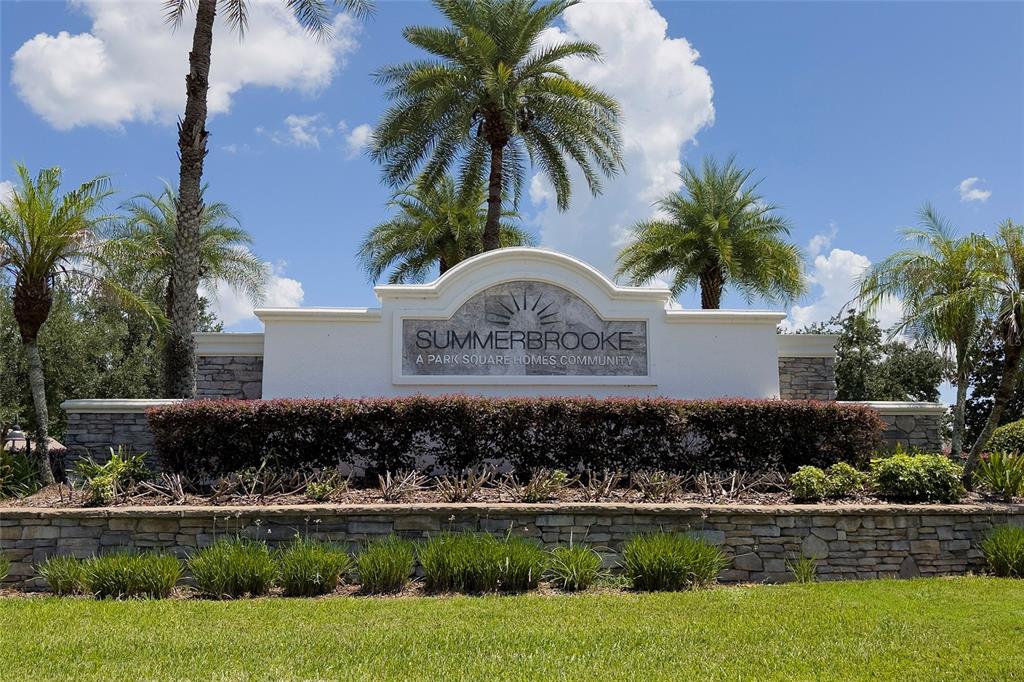 A stone-walled entrance sign for the Summerbrooke community features palm trees against a blue sky — 2336 NATOMA BOULEVARD, MOUNT DORA, FL