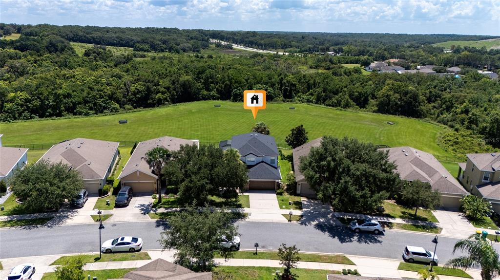 An aerial view shows a suburban house with a dark roof bordering a large grassy field — 2336 NATOMA BOULEVARD, MOUNT DORA, FL