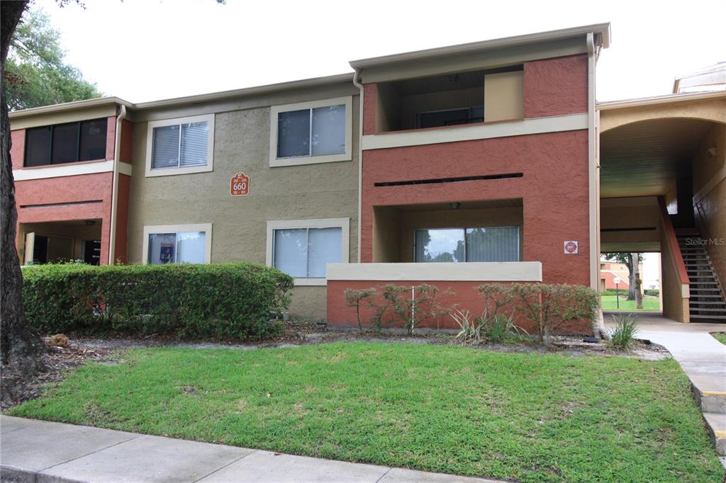 A two-story apartment building with stucco siding, balconies, and an outdoor staircase — 660 KENWICK CIRCLE UNIT 104, CASSELBERRY, FL