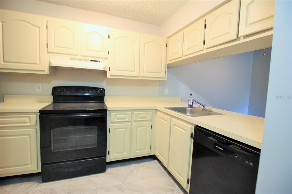 A kitchen features off-white cabinets, a black stove, a black dishwasher, and laminate countertops — 660 KENWICK CIRCLE UNIT 104, CASSELBERRY, FL