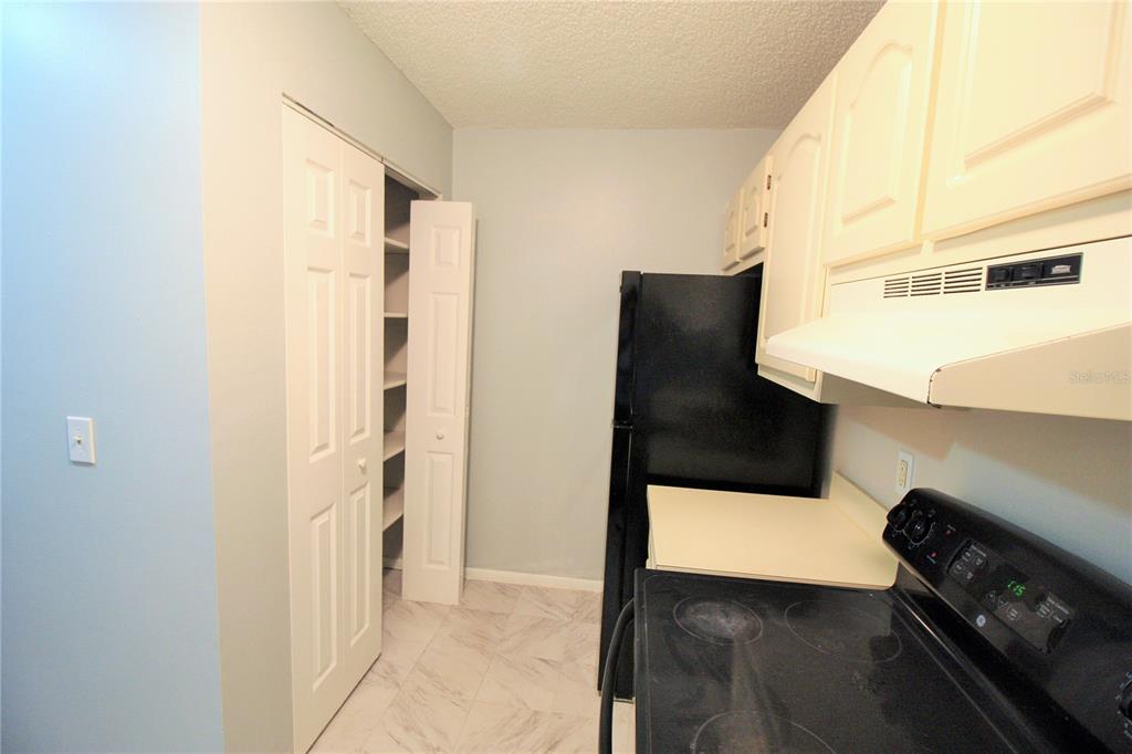 A kitchen features white cabinets, a black refrigerator, a black stove, and a pantry closet — 660 KENWICK CIRCLE UNIT 104, CASSELBERRY, FL