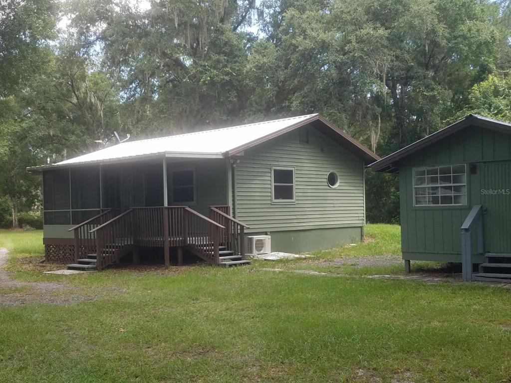 A green house with a white metal roof, a screened porch, and a detached shed — 40841 LOUISE ROAD, UMATILLA, FL