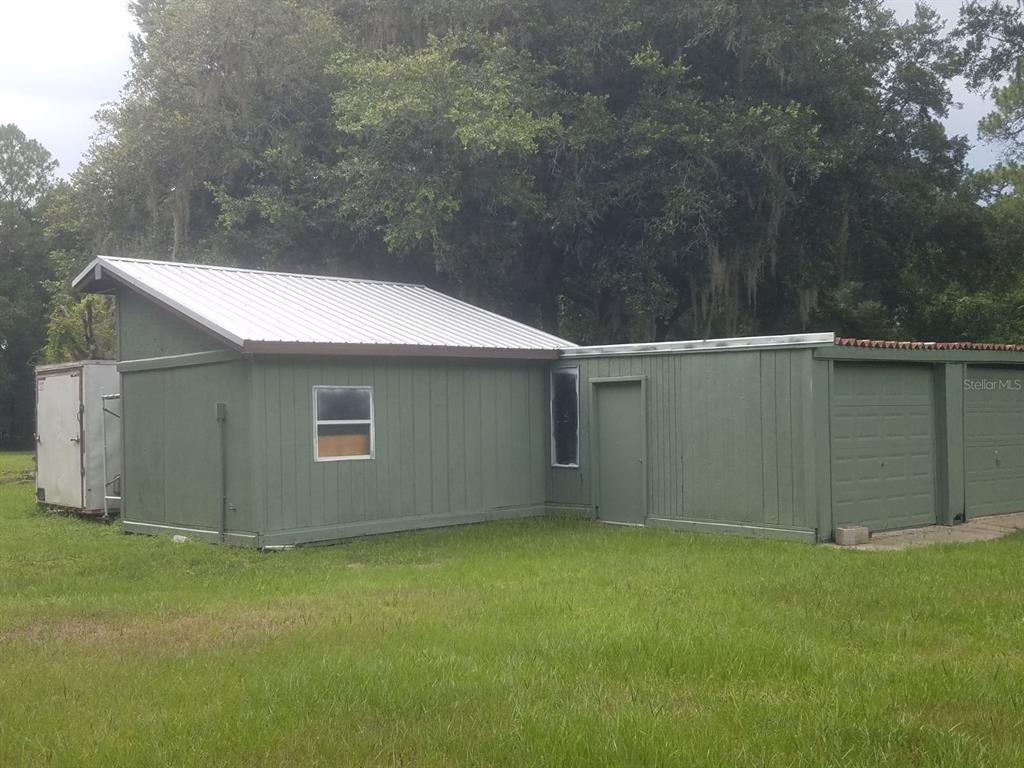 A green exterior building with a metal roof and an attached garage sits on grass — 40841 LOUISE ROAD, UMATILLA, FL
