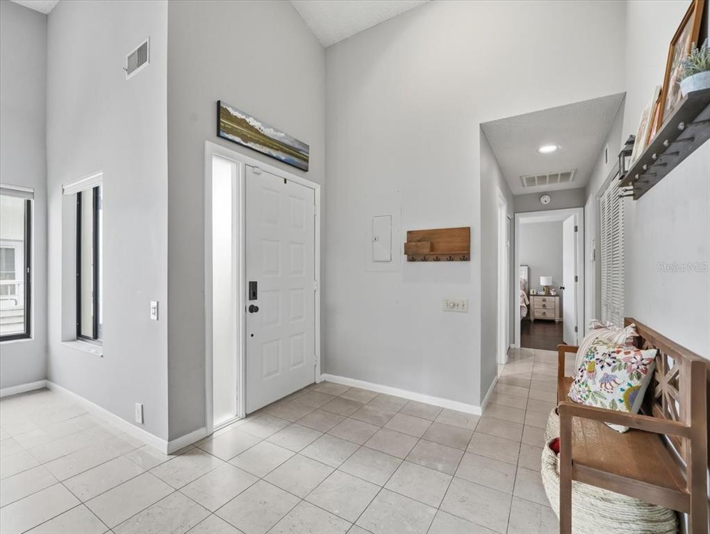 An entryway with light-colored tile flooring, a white front door, and a wooden bench — 1816 LAKE CYPRESS DRIVE UNIT 1816, SAFETY HARBOR, FL