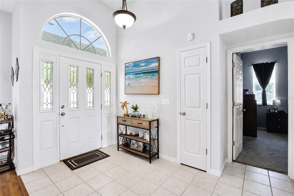 A bright entryway features a white front door with sidelights, tile flooring, and a console table — 2409 DANA DRIVE, SAFETY HARBOR, FL