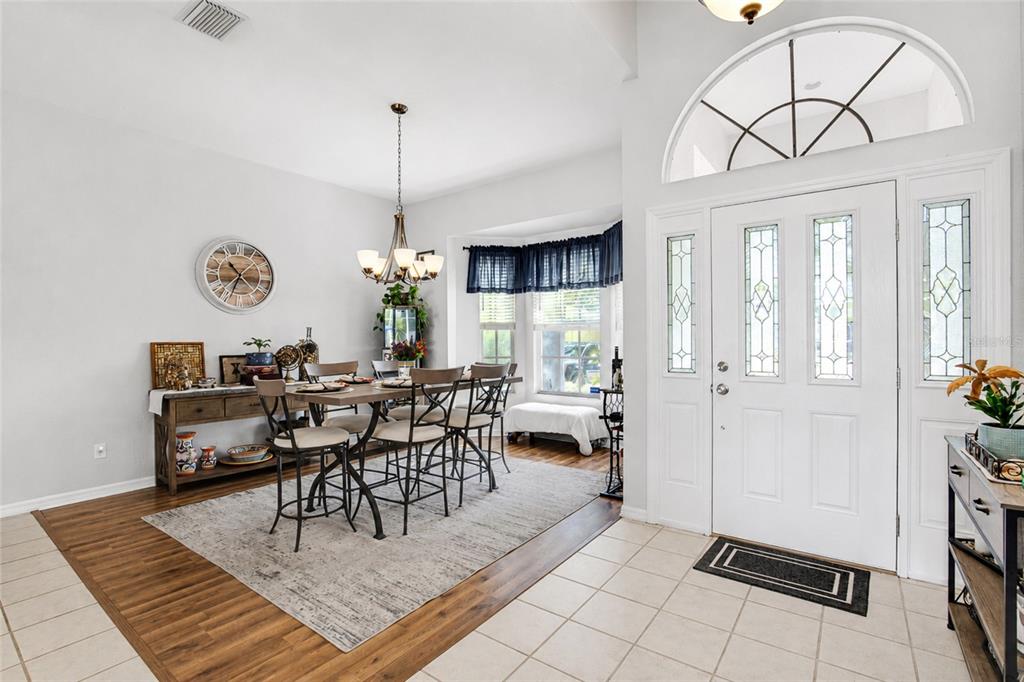 A dining area with a wooden table and chairs sits adjacent to a tiled entryway — 2409 DANA DRIVE, SAFETY HARBOR, FL