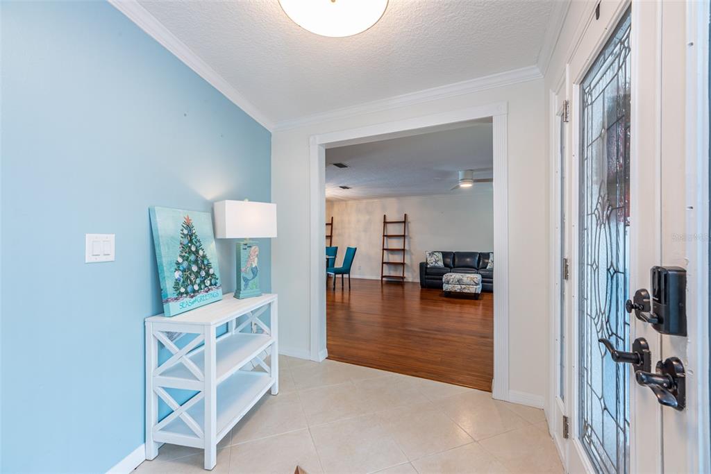 An entryway with a light blue wall, white console table, and view into a living room — 910 CHIPAWAY DRIVE, APOLLO BEACH, FL