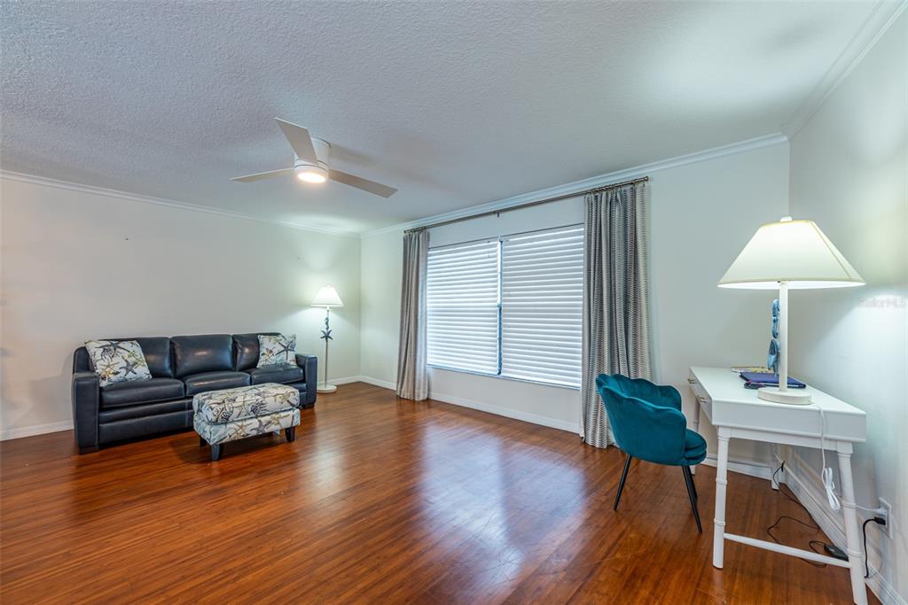 A living room with hardwood floors, a dark leather sofa, and a white writing desk — 910 CHIPAWAY DRIVE, APOLLO BEACH, FL