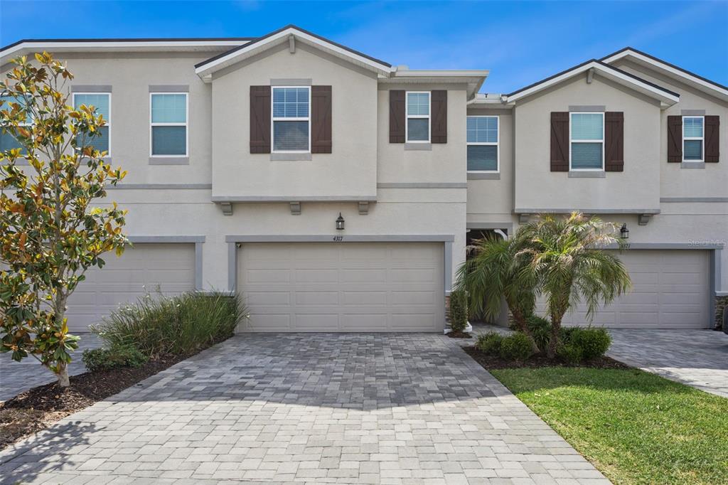 The exterior of a two-story townhouse features a paved driveway, two-car garage, and stucco siding — 4317 CLOUD HOPPER WAY, LUTZ, FL