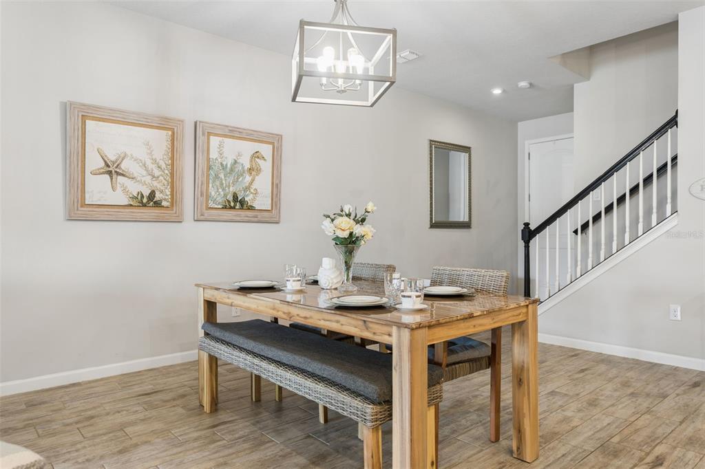 A dining room features a wooden table with a bench, wicker chairs, and a chandelier — 4317 CLOUD HOPPER WAY, LUTZ, FL