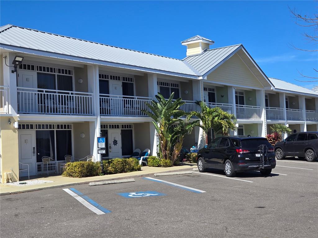A two-story building with white railings, a metal roof, and a handicap-accessible parking space — 611 DESTINY DRIVE UNIT 101, RUSKIN, FL