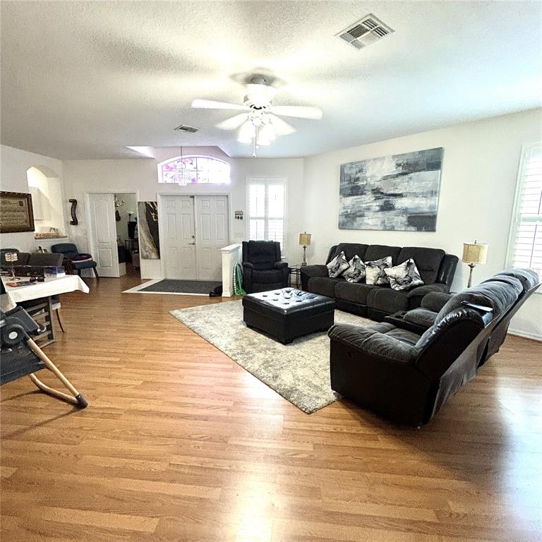 A living room features wood flooring, a ceiling fan, and dark gray upholstered furniture — 30236 LETTINGWELL CIRCLE, WESLEY CHAPEL, FL