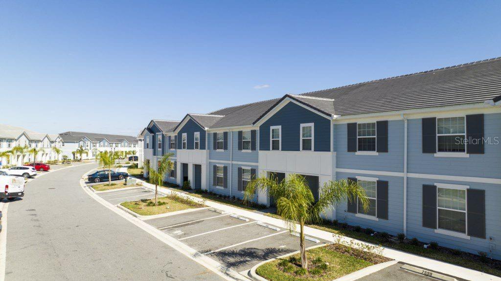 An exterior view of a two-story apartment building with blue siding and parking spaces — 7586 OAK SPRING LANE, DAVENPORT, FL