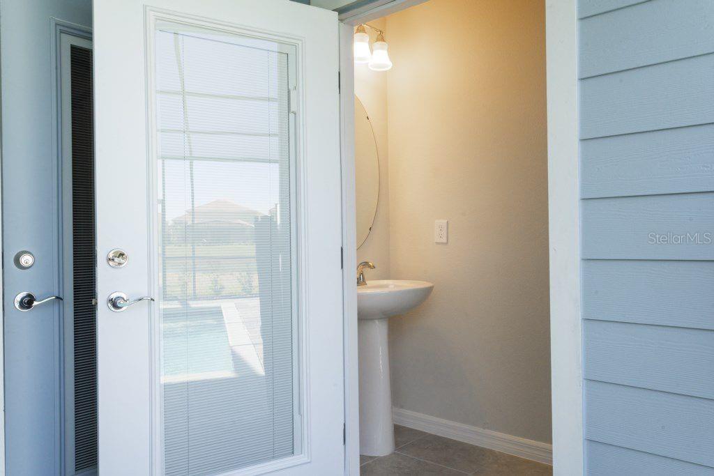 A white pedestal sink sits in a small bathroom viewed through an open glass door — 7586 OAK SPRING LANE, DAVENPORT, FL
