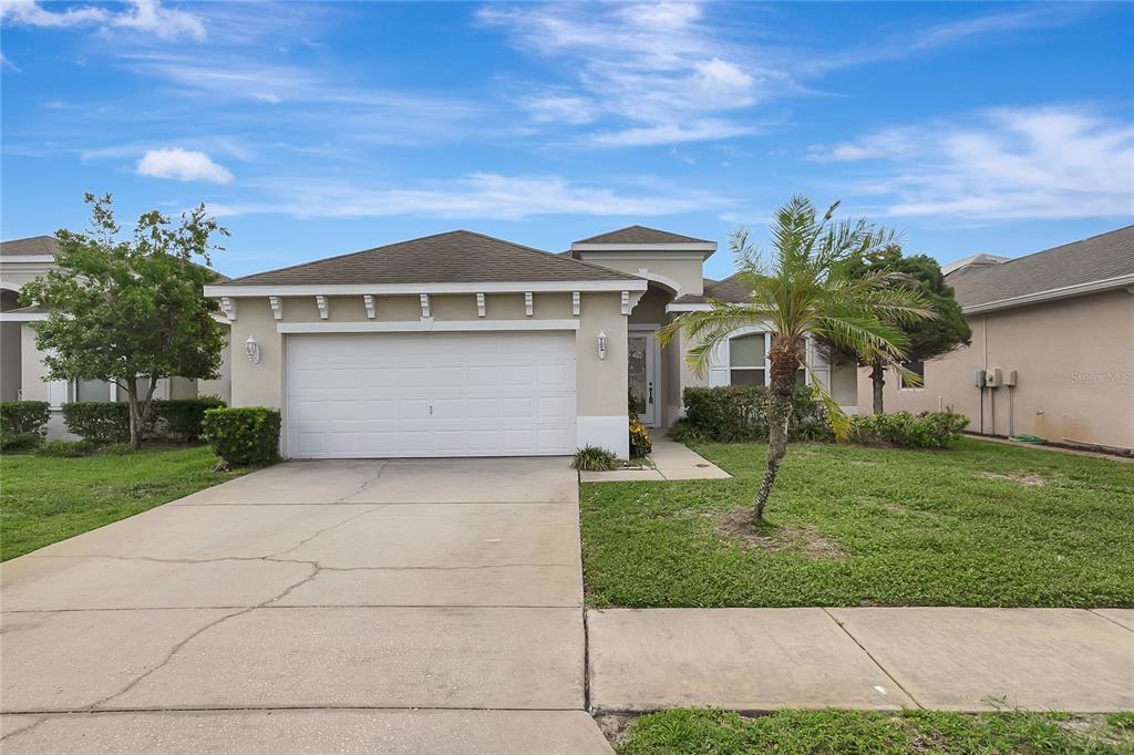 A single-story house with a two-car garage, a palm tree, and a concrete driveway — 14551 POTTERTON CIRCLE, HUDSON, FL