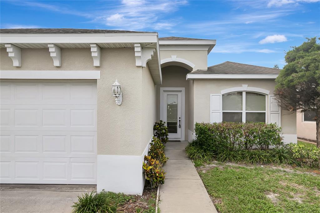 The exterior of a single-story house features a garage, a front entrance, and landscaping — 14551 POTTERTON CIRCLE, HUDSON, FL