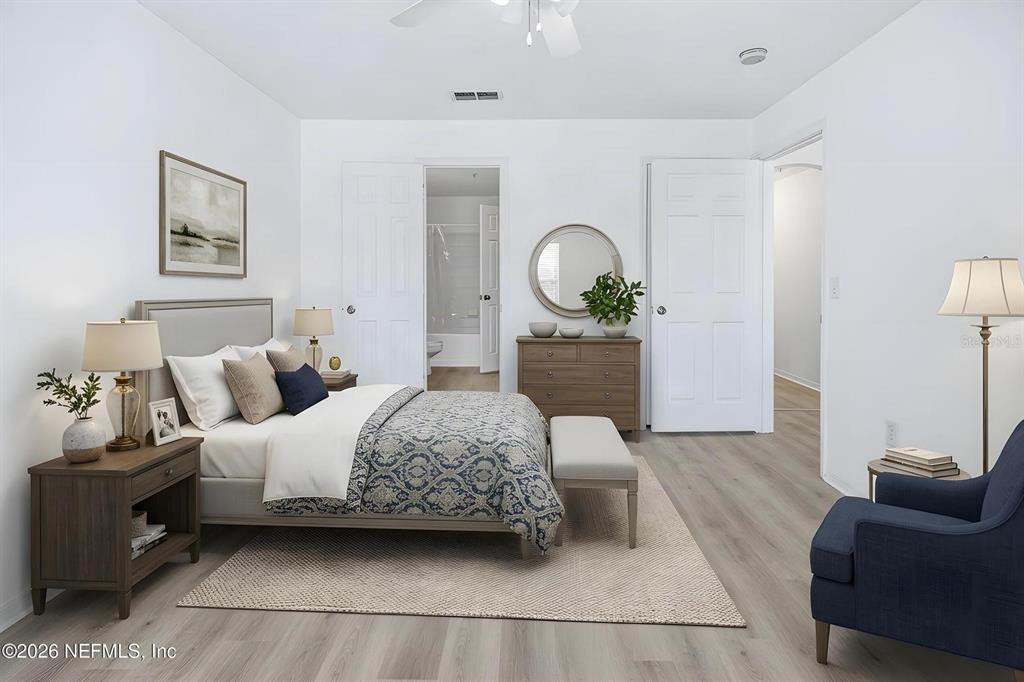 A bedroom features a bed, dresser, armchair, and light wood-look flooring in a neutral space — 7800 POINT MEADOWS DRIVE UNIT 737, JACKSONVILLE, FL