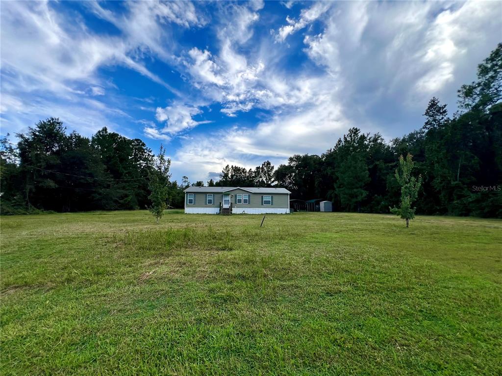 A single-story manufactured home sits in the middle of a large, grassy field — 113 SABRINA LN, PALATKA, FL