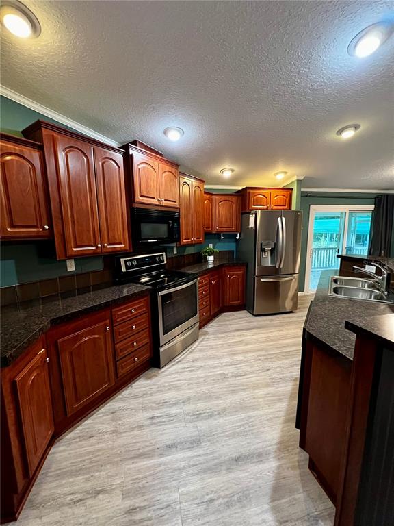 A kitchen features dark wood cabinets, stainless steel appliances, and dark countertops — 113 SABRINA LN, PALATKA, FL