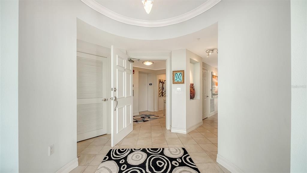 A tiled entryway features a white door, a circular ceiling detail, and a patterned rug — 409 NORTH POINT ROAD UNIT 401, OSPREY, FL