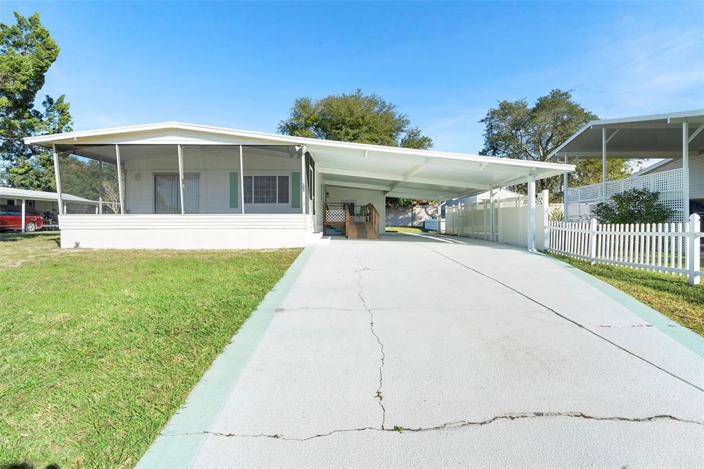A single-story manufactured home features a screened-in porch, a carport, and a concrete driveway — 105 FLORENCE BOULEVARD, DEBARY, FL