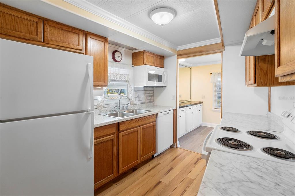 A kitchen with wood cabinets, white appliances, and marble-look countertops — 105 FLORENCE BOULEVARD, DEBARY, FL