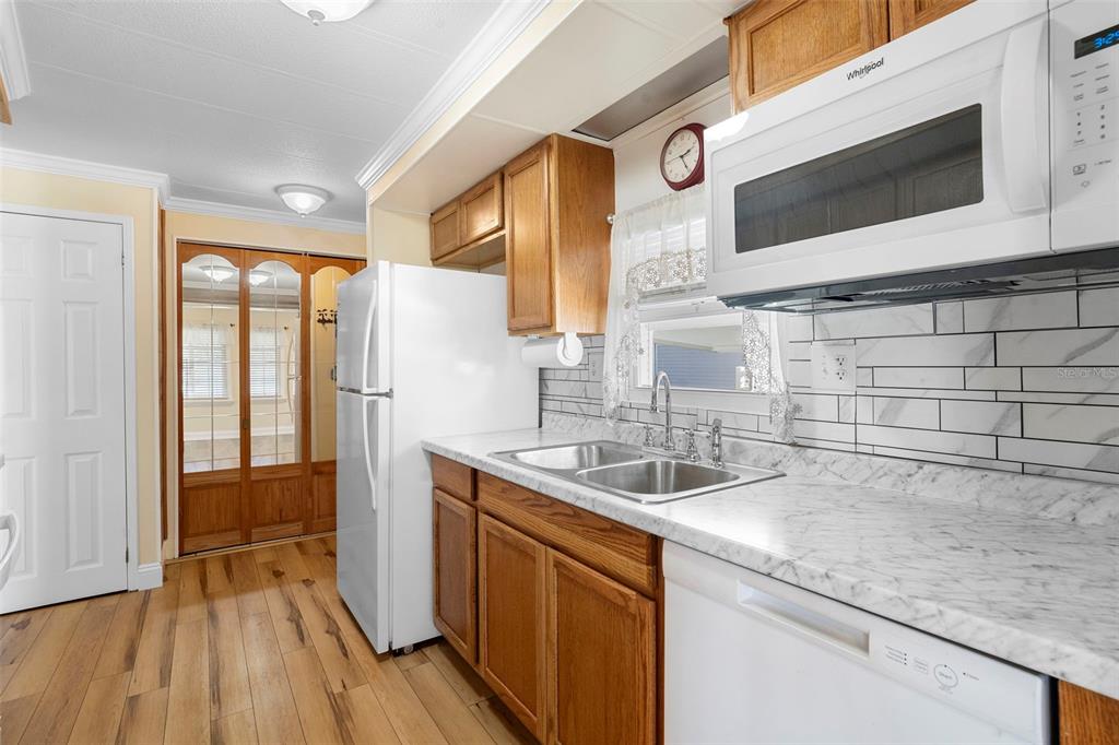 A kitchen features wood cabinets, white appliances, marble-look countertops, and a subway tile backsplash — 105 FLORENCE BOULEVARD, DEBARY, FL