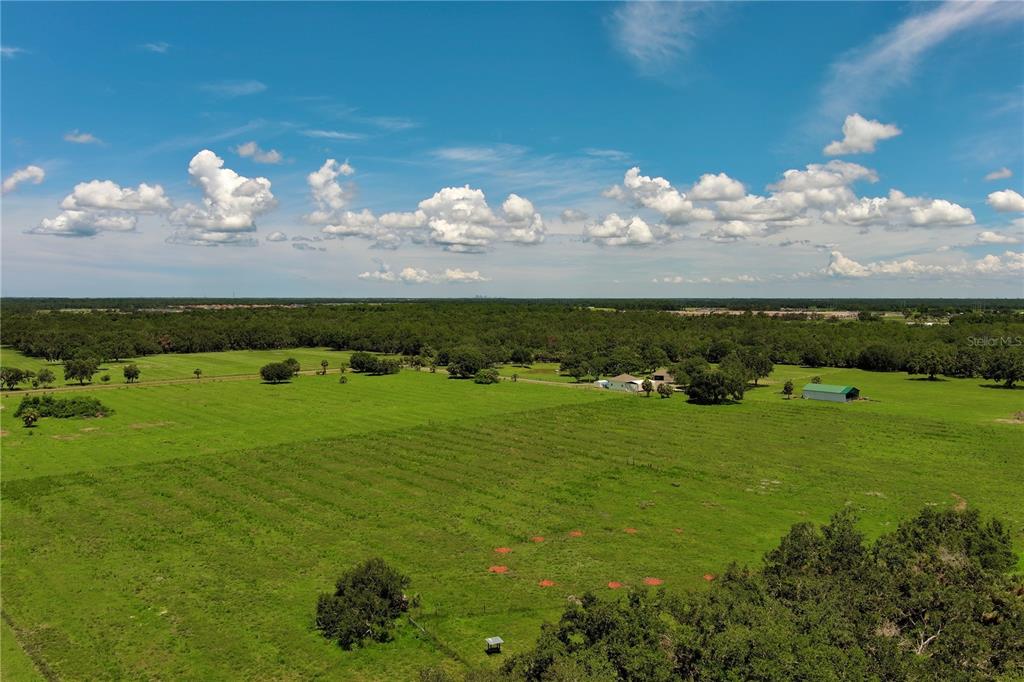 An aerial view shows a large, grassy pasture with scattered trees and a few small buildings — 15820 COUNTY ROAD 675, PARRISH, FL