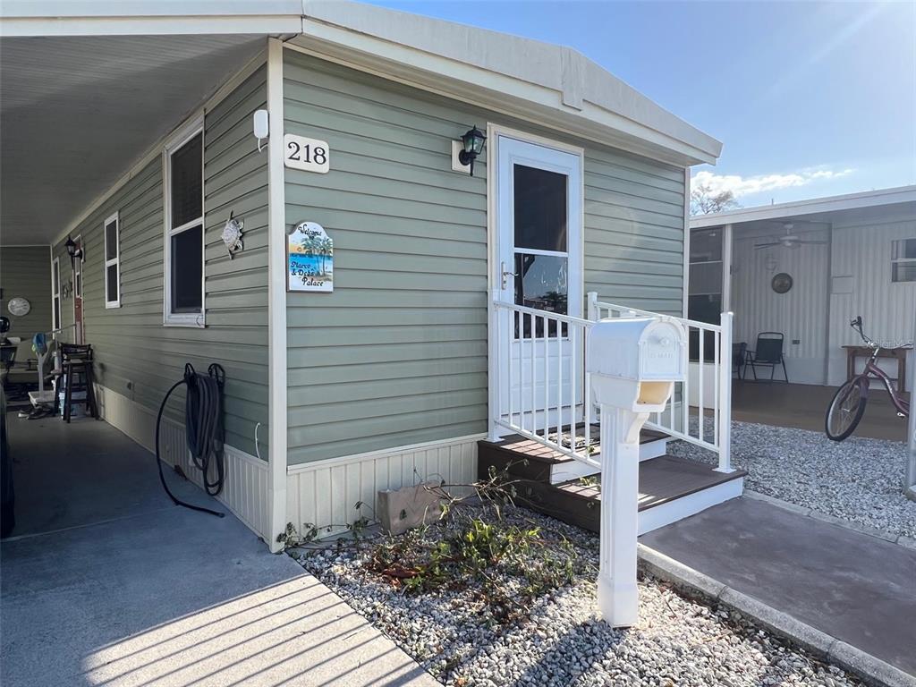A light green mobile home exterior features a white front door, mailbox, and carport — 8300 SEMINOLE BOULEVARD UNIT 218, SEMINOLE, FL