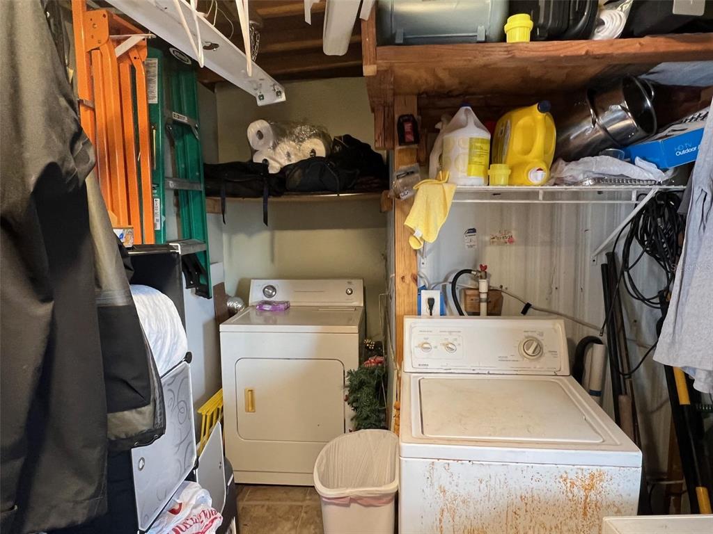 A laundry area features a white top-load washer and dryer with overhead storage shelving — 8300 SEMINOLE BOULEVARD UNIT 218, SEMINOLE, FL