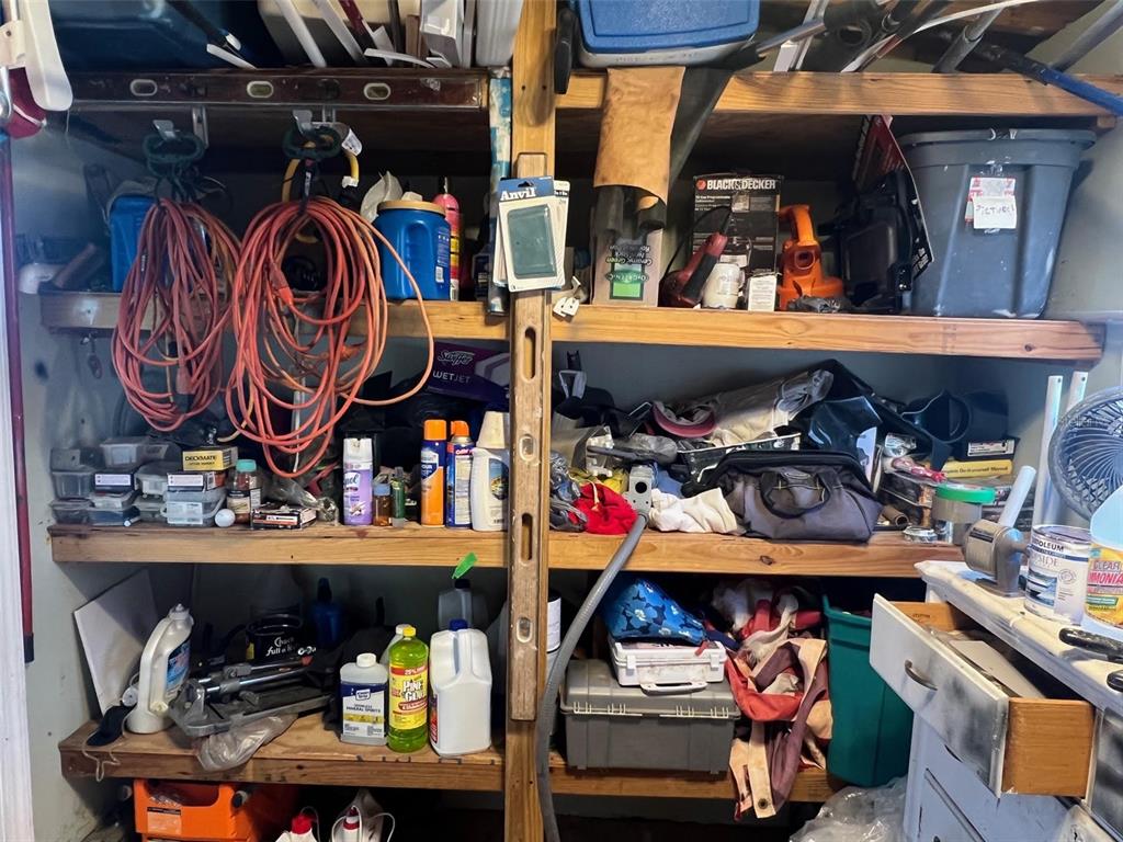 A cluttered storage closet features wooden shelves filled with various tools, containers, and household items — 8300 SEMINOLE BOULEVARD UNIT 218, SEMINOLE, FL