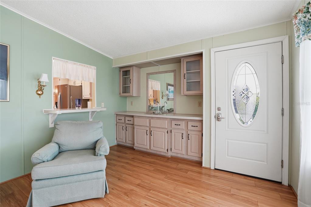 A room with light green walls, wood-look flooring, a wet bar, and a front door — 452 SHARKS POINT, NORTH PORT, FL
