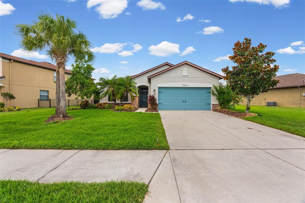 A single-story house with a blue garage door, a concrete driveway, and a palm tree — 5524 107TH TERRACE E, PARRISH, FL