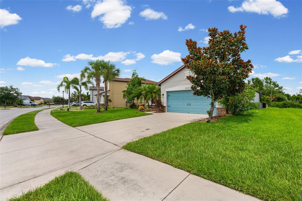 A single-story house with a blue garage door and a large tree in the front yard — 5524 107TH TERRACE E, PARRISH, FL