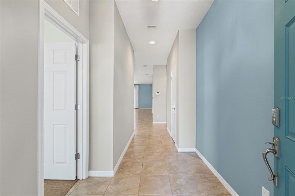 A tiled hallway leads from a blue-accented entryway toward an open living area — 5524 107TH TERRACE E, PARRISH, FL