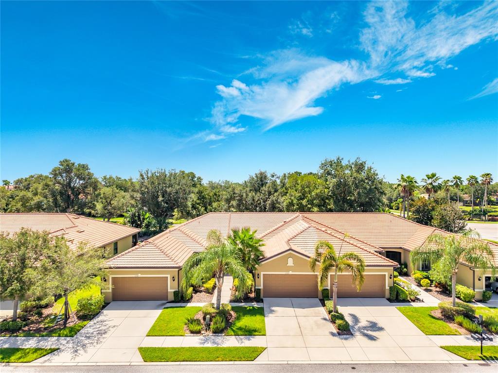An exterior view of a residential building with tiled roofs, garages, and landscaped front yards — 2590 OSWEGO DRIVE, NORTH PORT, FL