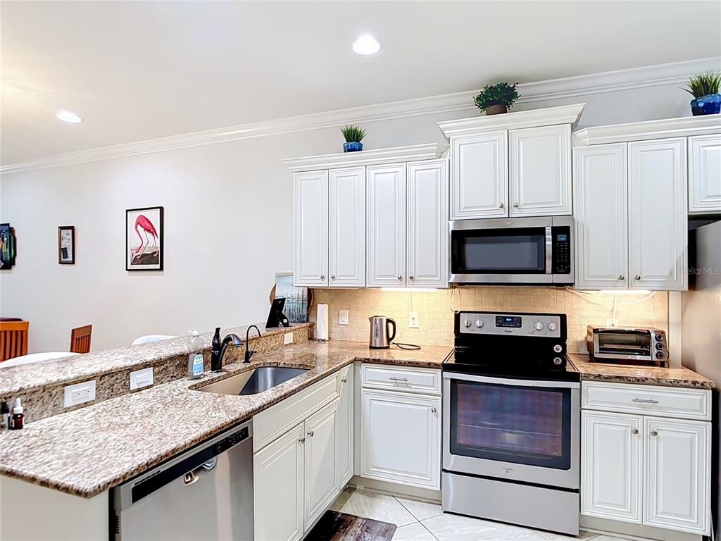 A kitchen features white cabinets, granite countertops, and stainless steel appliances — 2590 OSWEGO DRIVE, NORTH PORT, FL