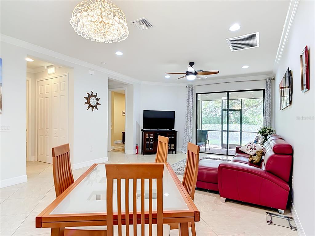 A dining area with a glass-top table opens into a living room with red furniture — 2590 OSWEGO DRIVE, NORTH PORT, FL